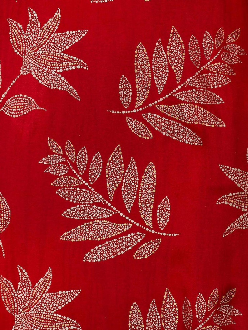 May include: Red fabric with a repeating pattern of gold leaf branches. The branches are made up of small, round dots.