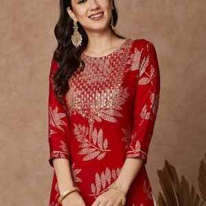 May include: A red kurta with a gold leaf print and gold embroidery. The kurta has a round neckline and three-quarter sleeves.