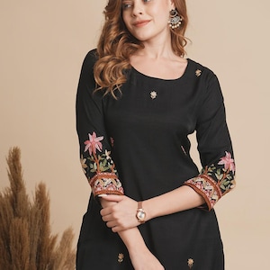 May include: A black long-sleeved kurta with floral embroidery on the sleeves and neckline. The kurta is made of a soft, flowing fabric and has a relaxed fit.