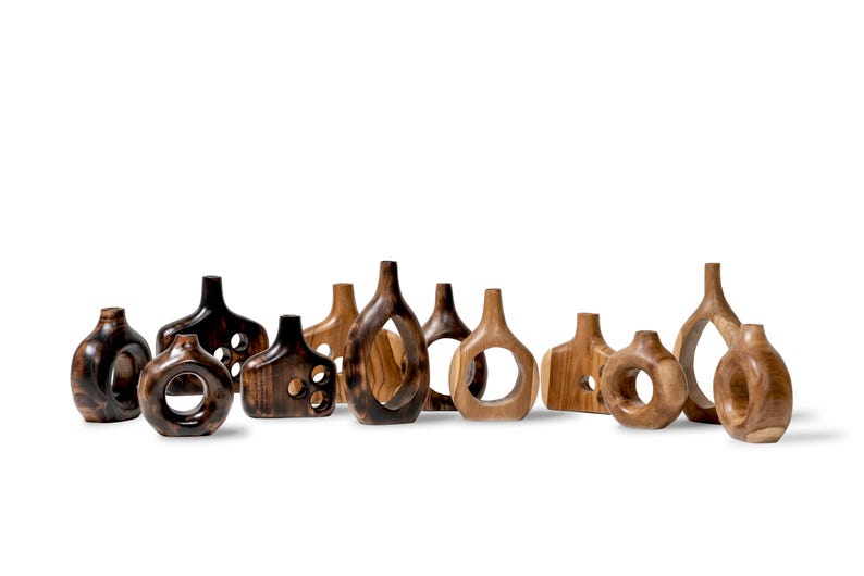 May include: A collection of wooden decorative vases in various shapes and sizes. The vases are made of different shades of wood, ranging from dark brown to light tan. Some have open circular or geometric cutouts.