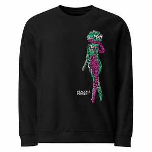 Könnte beinhalten: Schwarzes Sweatshirt mit einer Silhouette, die aus Wörtern wie "Frieden", "Königin" und "Macht" in Pink und Grün gebildet wird. Der Text "PEACEFUL POWER" ist unten auf dem Kleidungsstück aufgedruckt.