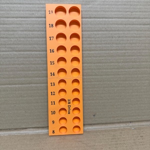 May include: Orange plastic tool organiser with 19 numbered slots for holding drill bits. The organiser is labelled "3/8 Drive".