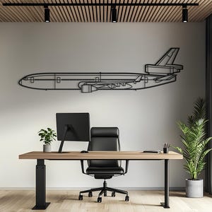 May include: A black metal wall art piece depicting the side profile silhouette of a wide-body jet aircraft. The design features clean, minimalist lines outlining the fuselage, wings, tail section, and engine placement of the airplane.
