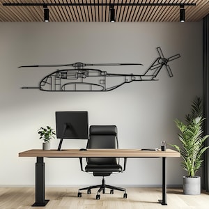 May include: A black metal wall art piece shaped like a helicopter silhouette, featuring detailed cutouts of the rotor blades, fuselage, engine, and tail rotor. The design is a flat, linear representation of an aircraft mounted on a plain wall.
