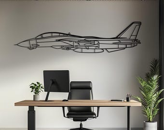 May include: A black metal wall art piece shaped like a fighter jet in profile. The silhouette features detailed outlines of the cockpit, wings, tail fin, and under-wing armaments. The design is mounted horizontally on a plain wall above a desk.