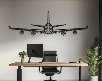 May include: A black metal wall art piece shaped like the front view of a four-engine commercial aeroplane. The design features a symmetrical silhouette with a central fuselage, long wings, and four circular engine outlines mounted on the wings.