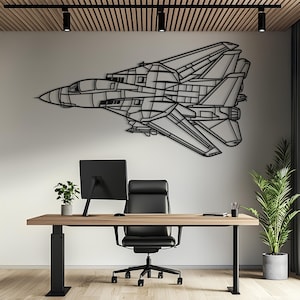 May include: A black metal wall art piece shaped like a fighter jet with detailed geometric panel lines and wing structures. The silhouette features a pointed nose, a cockpit canopy, and swept-back wings, mounted horizontally on a plain wall.