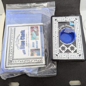 May include: A quilting kit featuring a black and white pounce, a blue chalk refill, and a pamphlet. The pounce is labelled "Quilt Pounce by Hancy" and has a blue chalk dispenser. The pamphlet is in a plastic bag and has the text "Quilt Pounce with Blue Chalk".