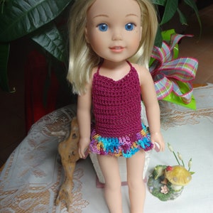 May include: A doll wearing a crocheted swimsuit with a burgundy top and a multi-colored ruffled bottom.