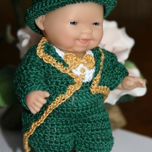 Peut inclure: Une poupée en crochet portant une tenue verte et dorée avec un trèfle sur le chapeau. La poupée porte un nœud papillon blanc et des chaussures noires.