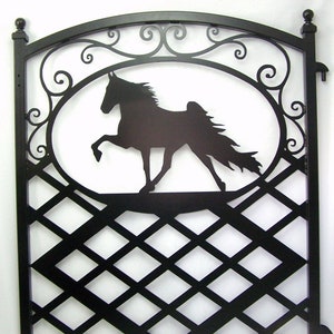 May include: Black metal gate with a diamond pattern and a silhouette of a horse in an oval frame. The gate has a decorative arched top with scrollwork.