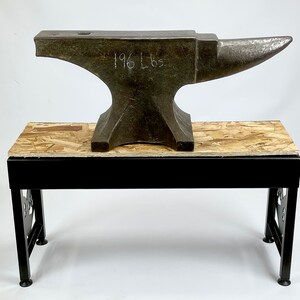 Pode incluir: Uma bigorna grande e resistente com uma base de metal preto e uma parte superior de madeira. A bigorna &eacute; feita de ferro e tem uma parte superior arredondada. A bigorna est&aacute; etiquetada com "196 Lbs".
