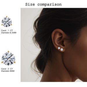 May include: A side-by-side comparison of two diamond stud earrings. The text indicates the size comparison, with one earring at 1 CT and 6.5MM diameter, and the other at 2 CT and 8MM diameter. One earring is shown on an ear.