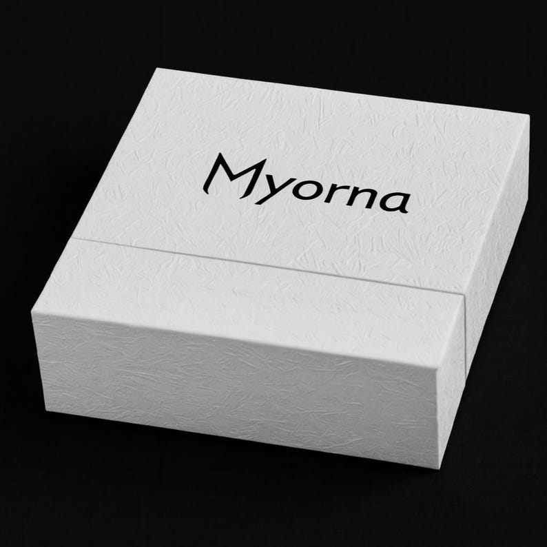 May include: A white textured box with the word "Myorna" printed in black on the top. The box is rectangular and has a lid that fits over the base. The background is black.