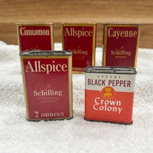 May include: Vintage spice tins with red and gold labels. The labels read "Cinnamon", "Allspice", "Cayenne", and "Black Pepper". The "Allspice" tin reads "2 ounces". The "Crown Colony" tin reads "1 1/2 ounce net".
