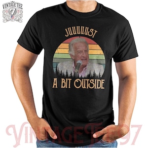May include: Black t-shirt with a retro design. The shirt features a portrait of a man and the text "JUUUUUST A BIT OUTSIDE". A vintage logo is in the upper left corner of the shirt.
