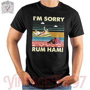 May include: A black t-shirt with a vintage-style graphic of two people in a boat with the text "I'm Sorry Rum Ham!"