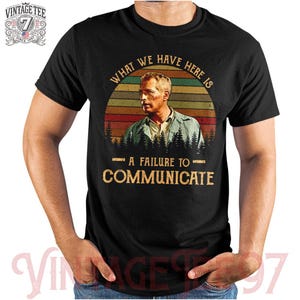 May include: A black t-shirt with a vintage-style graphic of a man with the text "What we have here is a failure to communicate."