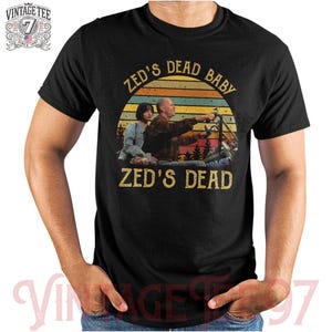 May include: Black t-shirt with a vintage-style graphic of two people riding a motorcycle. The graphic includes the text "Zed's Dead Baby" and "Zed's Dead".