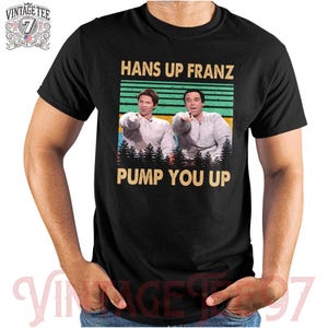 May include: A black t-shirt with a vintage-style graphic of two men with the text "Hans Up Franz Pump You Up".