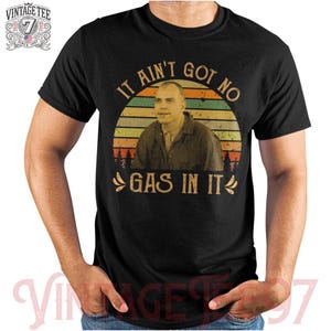 May include: A black t-shirt with a vintage-style graphic of a man with the text "It ain't got no gas in it".