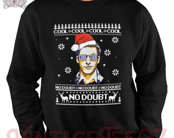 May include: Black Christmas sweater with a white snowflake pattern. The sweater features a cartoon image of a man wearing a Santa hat and sunglasses with the text "Cool Cool Cool Cool No Doubt" printed on the sweater.