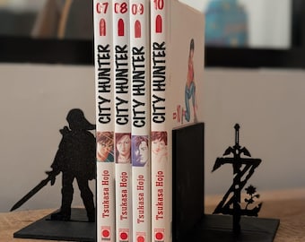 May include: Four City Hunter manga volumes numbered 07 through 10 by Tsukasa Hojo, held between two black metal bookends. The left bookend features a silhouette of a character with a sword, and the right bookend displays a stylized letter Z.