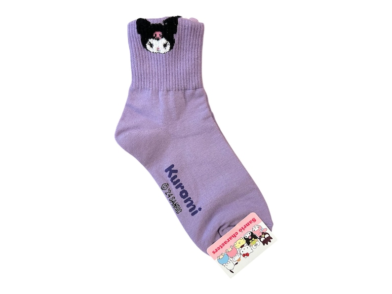 May include: Purple ankle socks with a black and white Kuromi character embroidered on the top. The socks have the text "Kuromi &copy;'21 SANRIO" printed on the side. The socks have a pink tag with the text "Sanrio Characters" and a group of Sanrio characters.