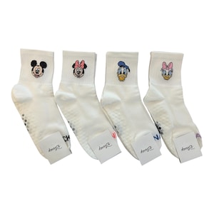 May include: Four pairs of white ankle socks featuring Disney characters Mickey Mouse, Minnie Mouse, Donald Duck, and Daisy Duck. Each sock has a character's face embroidered on the cuff. The socks have non-slip grips on the soles and Disney tags.