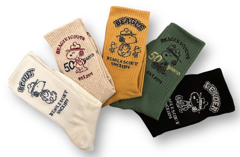 May include: Four pairs of white, yellow, green, and black socks with a cartoon dog wearing a scout hat and the text "BEAGLE SCOUTS" and "50 years" on them.