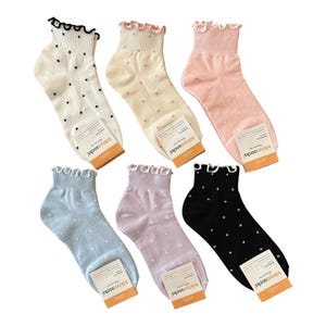 May include: Six pairs of ankle socks in various colors, each with a ruffled top and small polka dots. Colors include white, cream, pink, light blue, lavender, and black. Each sock has a tag that reads "kikiyosocks".