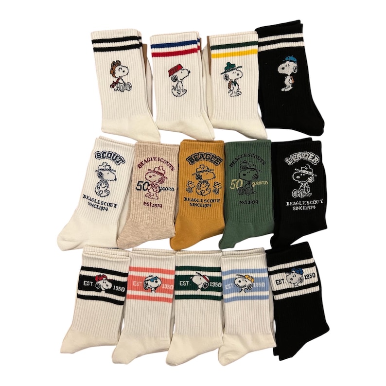 May include: A set of 10 pairs of white cotton socks with colorful stripes and embroidered Peanuts characters. The socks feature the text "BEAGLE SCOUTS" and "EST. 1950".