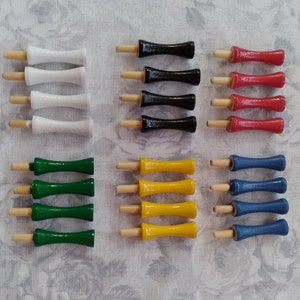 May include: A set of 10 wooden dowel rods with different colored tips. The tips are white, black, red, yellow, and blue. The dowel rods are arranged in rows of five.