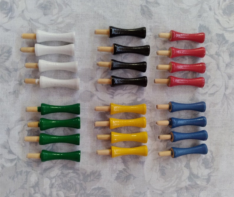 May include: A set of 10 wooden dowel rods with different colored tips. The tips are white, black, red, yellow, and blue. The dowel rods are arranged in rows of five.