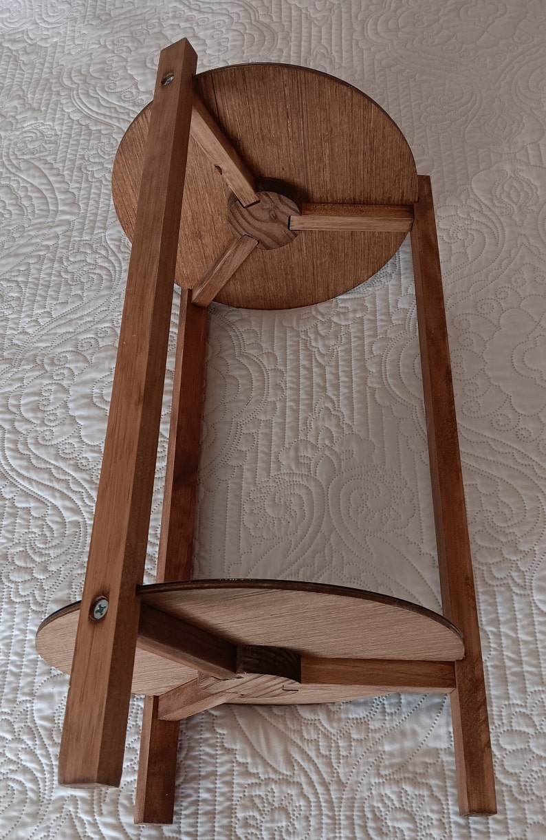 May include: A wooden side table with a round top and three legs. The table is made of light brown wood and has a simple design.