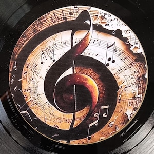 May include: A black vinyl record with a brown and gold treble clef design on the label. The design features musical notes and a vintage, aged paper background.