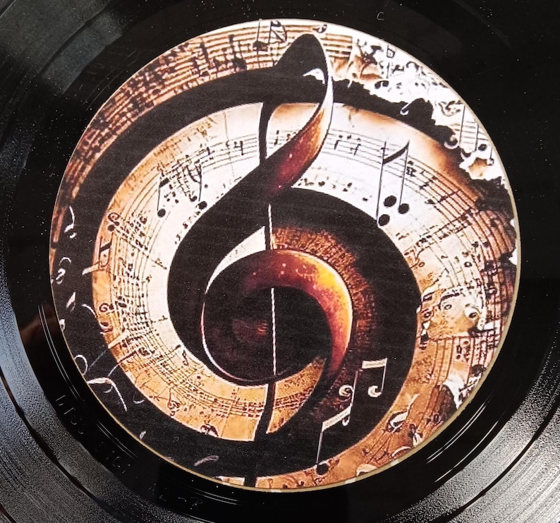 May include: A black vinyl record with a brown and gold treble clef design on the label. The design features musical notes and a vintage, aged paper background.