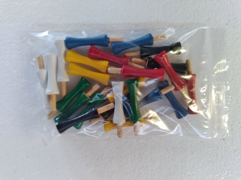 May include: A plastic bag filled with colorful wooden dowels. The dowels are in various colors, including red, blue, yellow, green, and white. The dowels are all the same size and shape, and they are arranged in a random order.