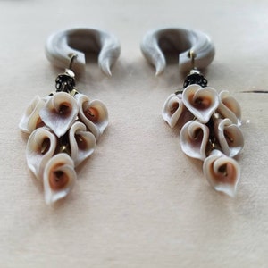 May include: A pair of white and brown heart-shaped dangle earrings with a white and gray wood-like base.