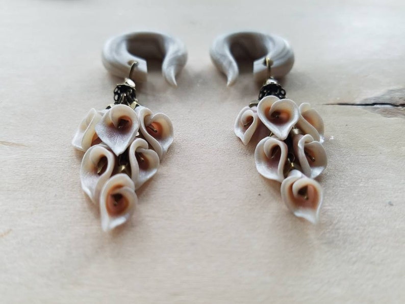 May include: A pair of white and brown heart-shaped dangle earrings with a white and gray wood-like base.