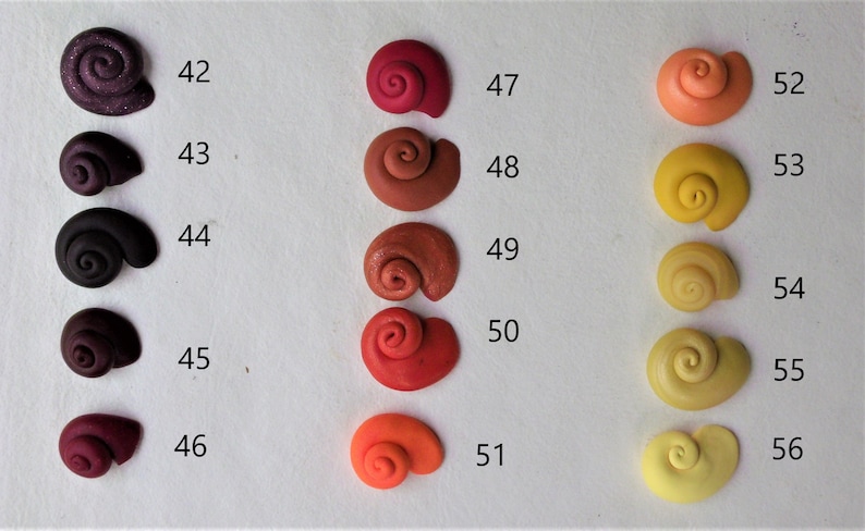 Peut inclure: Un ensemble de 14 petites coquilles d'escargots en c&eacute;ramique artisanales dans diff&eacute;rentes nuances de rouge, orange et jaune. Les coquilles sont num&eacute;rot&eacute;es de 42 &agrave; 56.