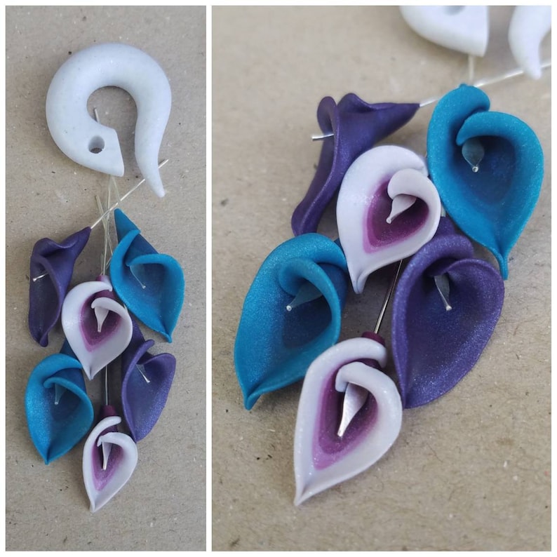 May include: A white hoop earring with a cluster of polymer clay flowers dangling from it. The flowers are in shades of teal, purple, and white.