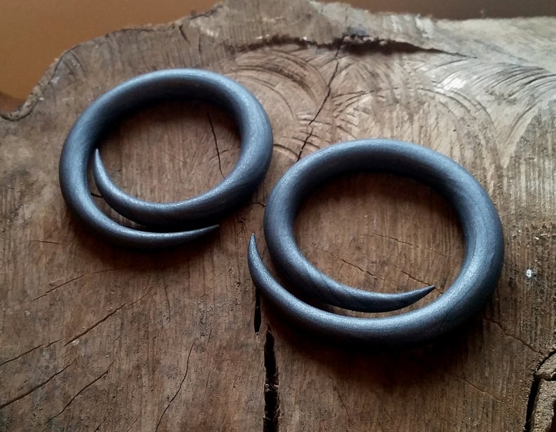 Peut inclure: Deux jauges d'oreille en bois spiral&eacute;es grises. Les jauges sont en bois et ont une finition lisse et polie.