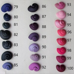 Peut inclure: Une collection de 18 petites coquillages en c&eacute;ramique faits &agrave; la main dans diff&eacute;rentes nuances de violet, rose et rouge. Les coquillages sont num&eacute;rot&eacute;s de 79 &agrave; 100.