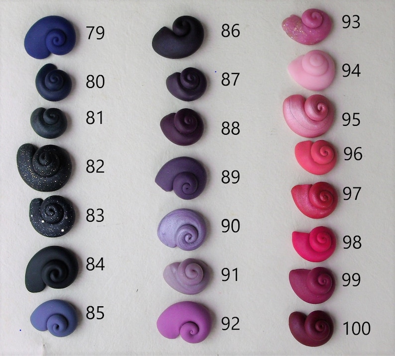 Peut inclure: Une collection de 18 petites coquillages en c&eacute;ramique faits &agrave; la main dans diff&eacute;rentes nuances de violet, rose et rouge. Les coquillages sont num&eacute;rot&eacute;s de 79 &agrave; 100.
