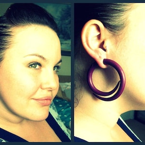 Peut inclure: Une femme aux cheveux fonc&eacute;s porte de grandes boucles d'oreilles en bois de couleur violette. Les boucles d'oreilles mesurent environ 5 cm de diam&egrave;tre.