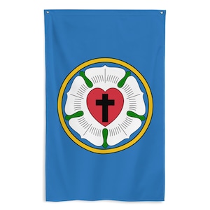 Könnte beinhalten: Eine blaue Flagge mit einem zentralen Emblem. Das Emblem zeigt eine weiße Rose, ein rotes Herz mit einem schwarzen Kreuz und einen gelben Ring. Die Flagge ist rechteckig mit Ösen oben zum Aufhängen. Das Design ist auf der Flagge zentriert.