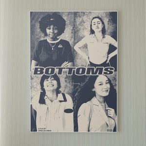 May include: A movie poster for the film "Bottoms" featuring four young women. The poster is in a black and white color scheme with a blue and white text overlay. The text reads "Bottoms" and "A film by Emma Seligman". The year "2023" is also included on the poster.