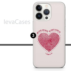 May include: A white iPhone case with a clear back. The case has a red heart-shaped fingerprint design with the text "We love because He first loved us 1 John 4:19".