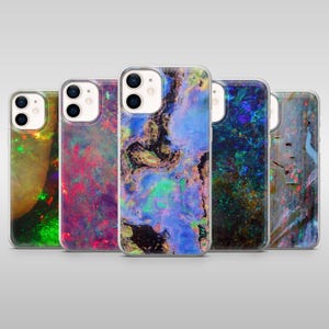 以下が含まれることがあります： オパール宝石を模した、カラフルな抽象デザインの携帯電話ケース5つ。ケースは透明で、背面にデザインが見えます。緑、赤、紫、青、金色の色が使われており、ユニークで芸術的な外観です。